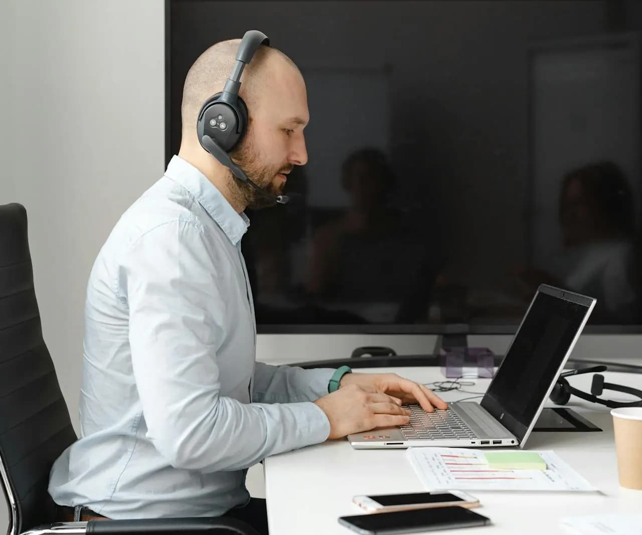 Call agent wearing headphones while working on a laptop