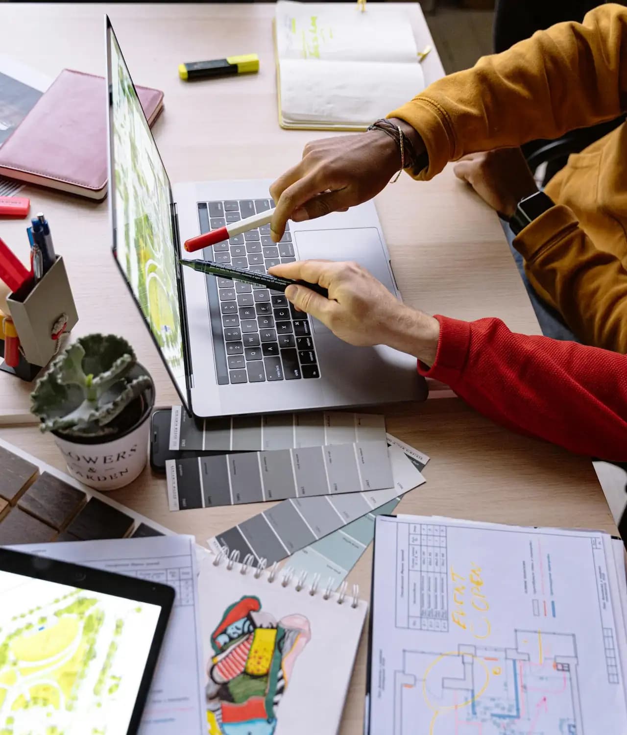 Designers collaborating on a laptop with color swatches and sketches